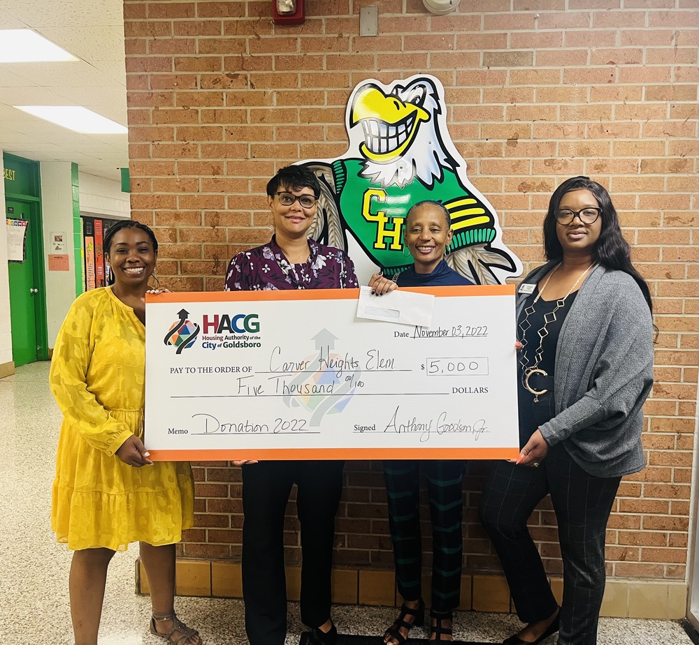 Goldsboro Housing Authority staff presenting the principal and staff at Carver Heights Elementary school a check.