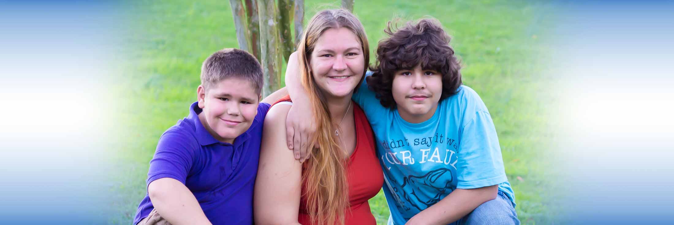 Mother and two sons posing under tree