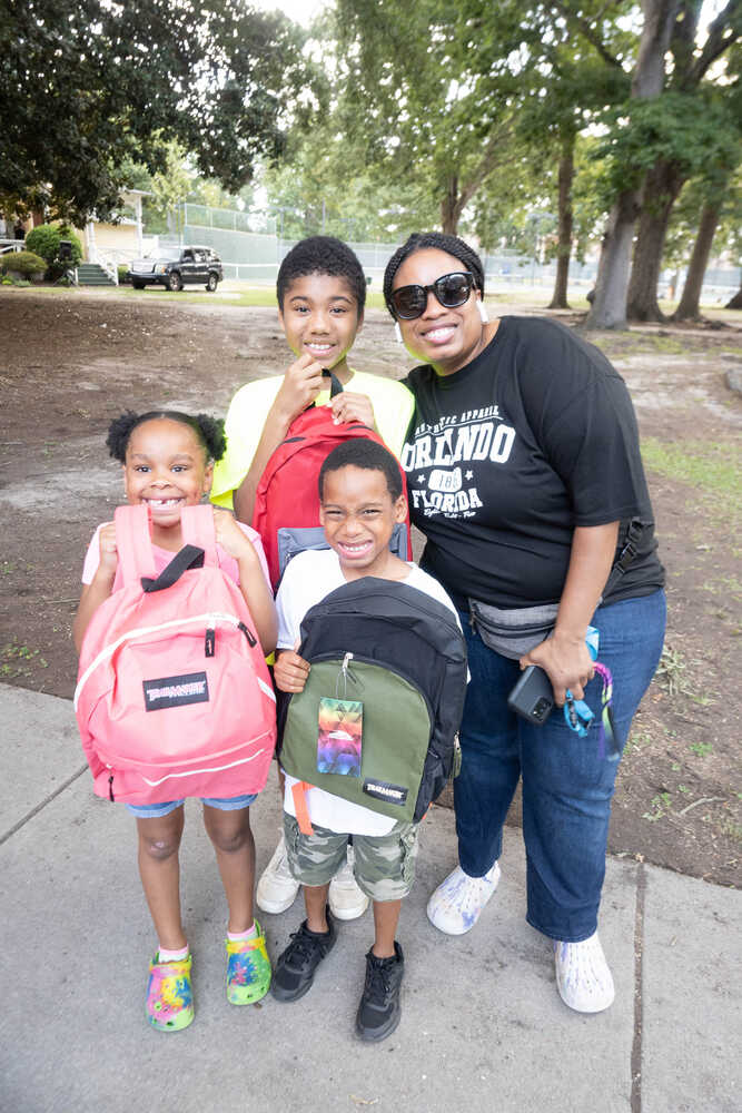Back to School Bash mother with 3 kids smiling with their new backpacks in hand
