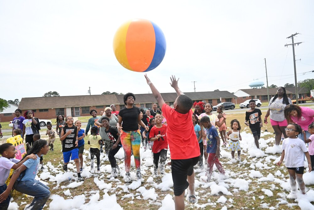 Foam party in Fairview with group of kids outside on lawn, foam on ground, and a beach ball in the air