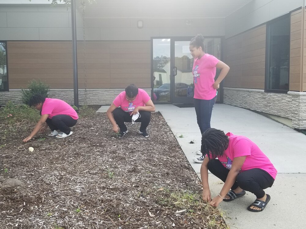 Teen Advisory Board group cleaning up Jobs Plus outside