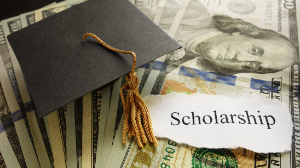 scholarship application with dollars and a graduation hat on top