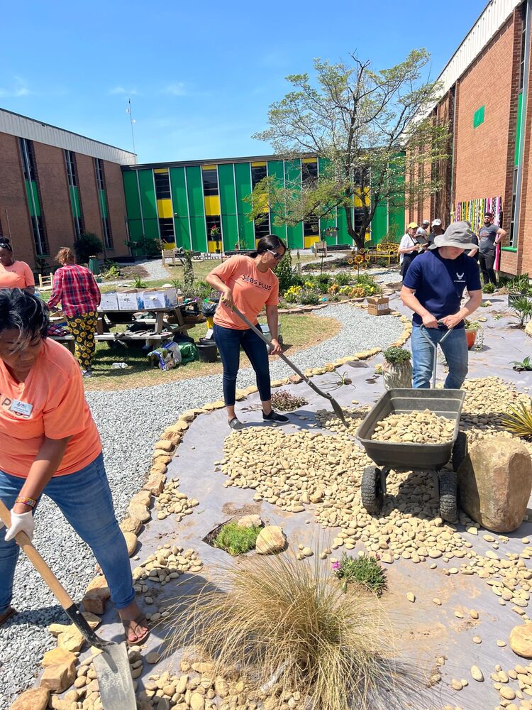 HACG Jobs Plus Staff are pictured shoveling rocks in the garden outside Carver Heights school. 